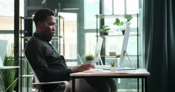 驚くべきアフリカ系アメリカ人のプロフェッショナルは 現代的なオフィスでの仕事に苦労しています 彼のビジネス努力への献身は 効率的で現代的なワークスペースに反映されています — ストック動画