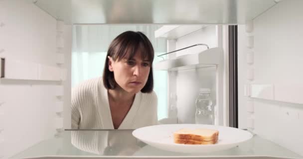 女性は冷蔵庫で腐ったサンドイッチの不快な臭いを発見することに不満を表します 彼女の反応は 腐った食べ物に対する彼女の失望を反映しています — ストック動画