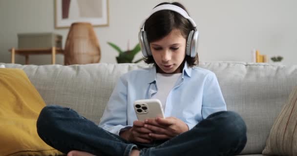 Chłopak Siedzący Kanapie Używa Telefonu Patrzy Kamerę Jego Bezpośredni Kontakt — Wideo stockowe