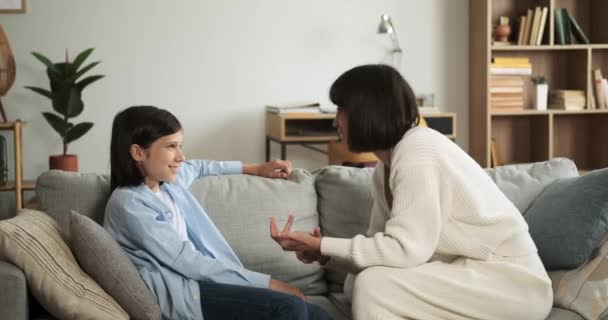 ジョイフルな母親と息子はリビングルームのソファーに座っている間 楽しい会話をします 彼らの笑顔とアニメーションの議論は 共有された幸福の雰囲気を生み出します — ストック動画