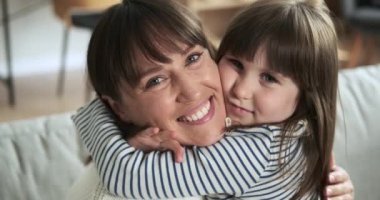 Sevgi dolu bir portre, gülümseyen bir anne ve kızın kanepeye oturup mutluluk ve sevgi saçarak kameraya baktığı bir anı yakalar..