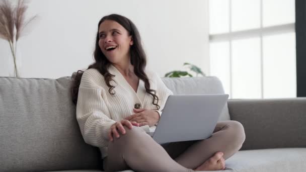 女人在一个视频通话中分享了一个真诚的笑声 眼睛闪烁着喜悦和真正的欢乐 房间里回荡着笑声 营造出一种具有传染性的欢乐气氛 — 图库视频影像