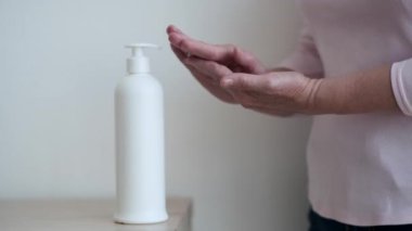 Nazikçe krem sürerken yaşlı bir kadının ellerini yakalar, parmakları hafif bir ritimle hareket eder. Her hareket tenin hassas dokusunu vurguluyor.