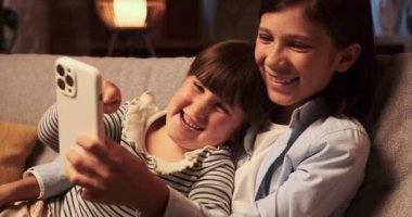 Akşam oturma odasının atmosferinde, bir erkek kardeş ve bir kız kardeş kanepede birlikte kaliteli zaman geçirirler. İkisi de akıllı telefonlara dalmış, kahkaha ve sohbet dünyasına dalıyorlar..