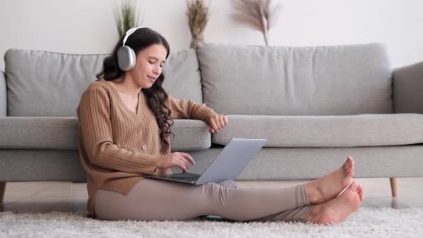 Kényelmesen Padlón Fejhallgatót Visel Zenét Hallgat Miközben Egyszerre Foglalkozik Laptoppal — Stock videók