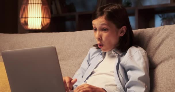 Young Schoolboy Sits Sofa Eyes Widened Astonishment Explores Wonders Laptop — Stock Video