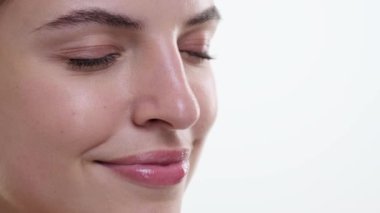 Neşeli beyaz kadın, beyaz bir arka plana karşı mutlulukla ışıldıyor. Gözleri sevinçle parıldıyor ve gülümsüyor, neşe ve neşe saçıyor..