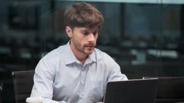 Odaklanmış işadamı büro masasında oturuyor, kağıtlar üzerine önemli notlar yazmaya dalmış. Kararlılık atmosferiyle çevrili, düşüncelerini titizlikle organize eder..