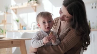 Anne mutfakta küçük oğlunu şefkatle kucaklıyor. Kollar onu saracak ve koşulsuz sevgiyle dolu güvenli bir sığınak yaratacak. Aralarındaki bağ aşikar ve oda şefkatle parlıyor gibi görünüyor..
