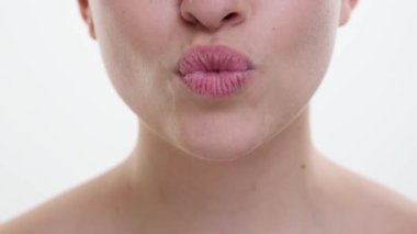 Bu samimi yakın planda kamera, saf beyaz bir arkaplan karşısında iki dudak buluşmasının büyüleyici anını yakalar. Görüntü, duyguların ve tutkunun derinliğini yansıtıyor..