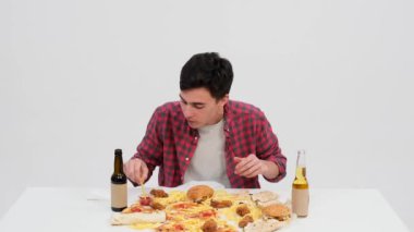 Kafkasyalı bir adam, el değmemiş beyaz bir arka planda kızarmış patatesin tadını çıkarıyor. Her lokmada, yüz, saf zevki yansıtır, zevki gösterir..