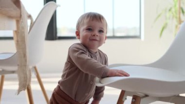 Küçük çocuk mutfakta sandalyeye yakın duruyor. Etrafındaki dünyayı izlerken gözleri merakla dolu. Erkeklerin varlığı uzaya gençlik enerjisi katıyor..