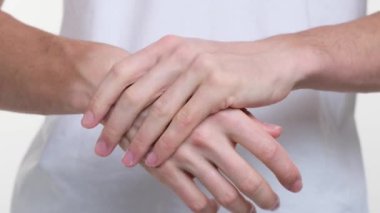 Kamera beyaz bir adamın ellerine odaklanıyor krem sürerken zarifçe. Her hareket kasıtlı ve naziktir. Cilt bakımına titiz bir yaklaşım sergiler..