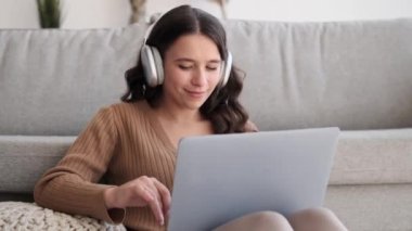 Oturma odasının rahatlığında, bir kadın dizüstü bilgisayara dalmış bir şekilde yerde oturuyor. Evinin alışık olduğu konforla çevrelenmiş halde, dijital görevleri odaklanarak ve kolaylıkla yürütür..