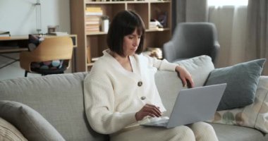 Kararlı kadın kanepede oturur, dizüstü bilgisayara dalmıştır. Odaklanmış ifadesi çalışmaya olan bağlılığını vurguluyor, sarsılmaz bir konsantrasyon sahnesi yaratıyor..