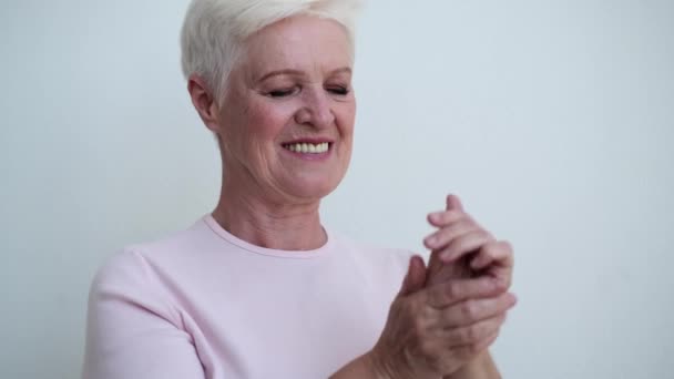 Die Lächelnde Ältere Frau Trägt Zart Handcreme Auf Die Augen — Stockvideo