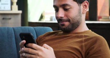 Adam bir telefon görüşmesi yaparken buzdolabına bakıyor. Çoklu görevleri günlük sorumluluklarla uğraşmayı, iletişimi ve ev işlerini dengelemeyi yansıtıyor..