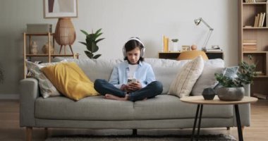 Öğrenci kanepede telefon kullanırken kulaklıkla müzik dinlemekten hoşlanır. Özümsenmiş ifadesi dinlemenin zevkini yansıtıyor, kişisel bir zevk sahnesi yaratıyor..