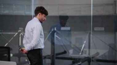 Düşünceli Kafkas işadamı ofisin penceresinin yanında düşünceli adımlarla yürüyor. İçsel bakışları ve ölçülü adımları konsantrasyonun derinliğini yansıtıyor..