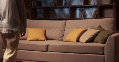 Yorgun beyaz kadın oturma odasındaki kanepenin yumuşak yastıklarına batıyor. Omuzları günlük aktivitelerin ağırlığını taşır ve gözler iyi harcanmış bir günün yorgunluğunu yansıtır..