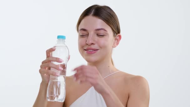 ジョイフルな白人女性は 水分補給の瞬間に明らかに 水瓶から爽やかな飲み物を取ります きれいな白い背景に対して コンテンツが輝きます — ストック動画