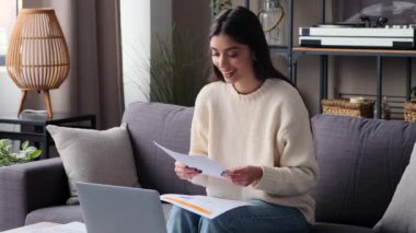 Oturma odasında video görüşmesi yaparken neşeli bir kadın gülümseyerek el sallıyor. Uzayın sıcak atmosferi, dostça atmosfere katılır ve hoş bir etkileşim anı yaratır..
