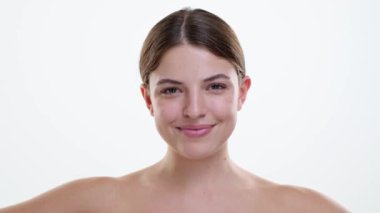 Neşeli beyaz kadın, yüzünde parlak bir gülümsemeyle diş fırçasına diş macunu sürüyor. Neşeli ifadesi basit diş bakımı hareketini geliştiriyor. Bunu mutluluk ve hijyen anına dönüştürüyor..