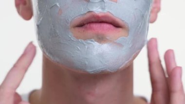Kamera, krem sürmüş bir adamın yüzüne yakınlaşıyor. Her detay, kremin pürüzsüz dokusu, titiz uygulama ve yüzündeki gevşek ifade olarak telaffuz edilir..