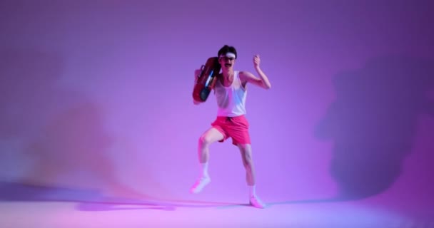 ハッピー80Sコーカサス人の男は 紫色の背景にカセットプレーヤーが伴うエキゾチュアランスで踊ります この活気に満ちたシーンは ダンスとポジティブなエネルギーのレトロな魅力を楽しい方法で捉えています — ストック動画