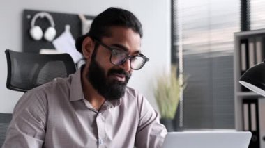 Profesyonel kıyafetli olumlu bir adam, ofiste bir iş videosu çekiyor. Olumlu ifadeler coşku ve verimliliği iletir, başarılı bir sanal işbirliği sahnesi yaratır..