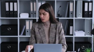 Beklenmedik bir kesintiyi yakalamış bir kadın ofis işi sırasında hapşırıyor ve hemen mendil kullanıyor. Bu görüntü, hijyen ve düşüncenin korunmasının önemini vurgular..