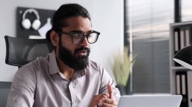 Pozitif iş adamı çalışma alanından online bir toplantıya katılıyor. Hevesli ifadeler ve meşgul davranışlar sanal etkileşimin işbirlikçi doğasını vurgular.