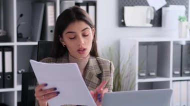 Adanmış beyaz kadın ofiste çalışırken video iletişimi kuruyor. Bu resim, net ve odaklanmış profesyonel etkileşimlere bağlılığı yansıtır.