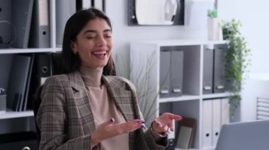 Gülen iş kadını video görüşmesi için dizüstü bilgisayardan faydalanıyor ve iş gününe neşe katıyor. Bu görüntü, onun profesyonel çevreye getirdiği pozitif ve neşeli enerjiyi yakalar..