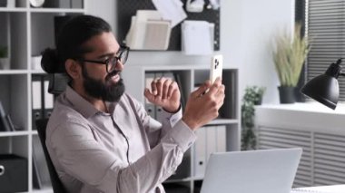 Ofiste çalışmaya ara veren Hintli bir adam bir video görüşmesi yapıyor. İfadeler mola sırasında bir rahatlama ve bağlantı karışımı iletir.