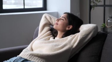 Kafkasyalı kadın evdeki konforlu kanepede dinleniyor. Rahatlamış atmosfer tatmin duygusunu vurguluyor, huzurlu bir huzur ortamı yaratıyor..