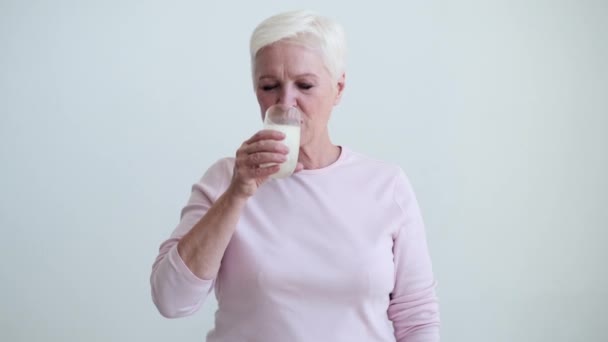 Den Äldre Vita Kvinnan Tar Försiktigt Klunk Mjölk Från Ett — Stockvideo