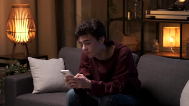 Oturma Odasındaki Kanepede Oturan Bir Adam Sıkılıyor Telefonu Tutarken Esniyor — Stok video