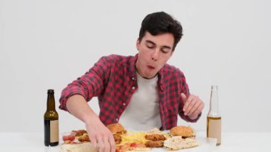 Aç adam bir dilim pizzaya hevesle bağlanır, sadece ondan önceki lezzetli yemeğe odaklanır. Temiz beyaz bir arkaplanda, her peynirli lokmanın tadını çıkarıyor..