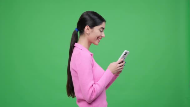 绿色背景的肖像描绘了一个拿着电话笑着的白人女人 她散发着喜悦和欢乐 充满了真诚的笑声和积极的能量 — 图库视频影像