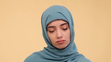 Kapalı bir portre, derin bir Arap kadını derin bir nefes alır bastırılmış bej bir arka plana karşı ağır bir nefes, derin bir tefekkür ve içgözlem hissi iletir dokunaklı bir ortamda.