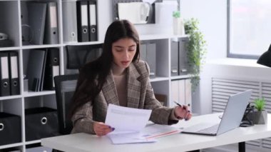 Neşe saçan, neşeli bir iş kadını coşkulu bir ofiste evrak işleriyle uğraşıyor. Şirket işyerine dinamik ve canlandırıcı bir atmosfer ekliyor..