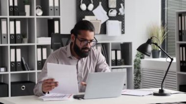 Hintli işadamı bir ofis ortamında işine odaklanıyor. Profesyonel giysiler, ciddi davranışlar, kendini adamışlık ve sorumluluklara bağlılığı yansıtır..