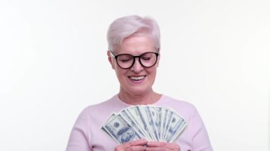 Gözlüklü son sınıf öğrencisi bir avuç dolusu para tutuyor ve mutlu bir ifade takınıyor. Gözleri mutluluk ve mutlulukla parlıyor. Neşeli tavırlar finansal tatmini yakalar..