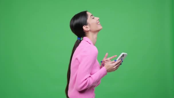 年轻的白人妇女上网 发短信 发短信 用电话进行在线娱乐 在绿色背景下大笑 — 图库视频影像