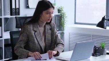 Beyaz kadın muhasebe işlerinden memnun değil. Belgeler ve dizüstü bilgisayarla birlikte. Yatırımları ve şirket bütçesini kontrol etmek, evrakları gözden geçirmek.