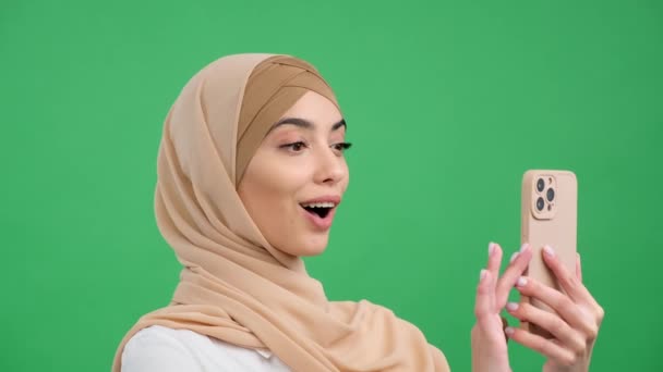 阿拉伯热情的女人通过在绿色背景的手机上浏览来庆祝好消息 庆祝成功 得到好消息 胜利的概念 — 图库视频影像