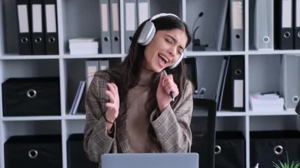 快乐的高加索女人 头戴耳机 听音乐 庆祝成功 为在现代办公室取得的成就感到高兴 — 图库视频影像