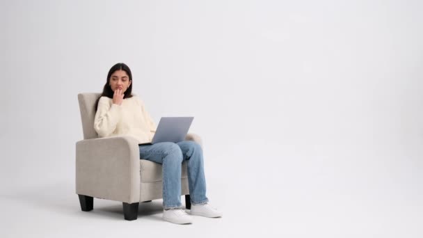 Düşünceli Beyaz Bir Kadın Elinde Dizüstü Bilgisayarla Bir Koltukta Oturuyor — Stok video