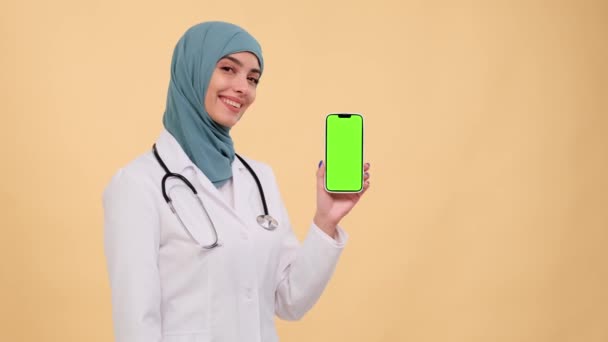 Médica Muçulmana Positiva Segurando Telefone Com Uma Tela Verde Apontando — Vídeo de Stock